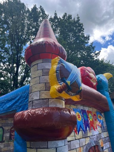 Drachenland Trum mit Schwert Bunte Hüpfburg mit einem Turm und einem Piratenmotiv im Freien.