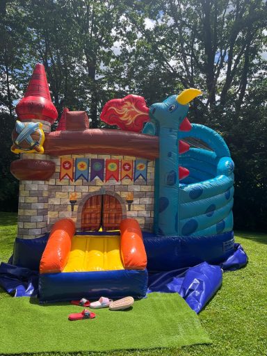 Hüpfburg Drachenland mit Rutsche vorne Bunte Hüpfburg in Form eines Schlosses mit Rutsche und Drachenmotiv.